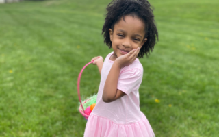 Annalise in a pink tutu shirt holding an Easter basket after participating in a Delaware Easter Egg hunt