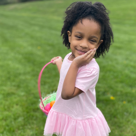 Annalise in a pink tutu shirt holding an Easter basket after participating in a Delaware Easter Egg hunt