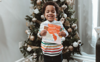 Deuce Harrison holding a Diverse Christmas Children's Book - The Snowy Day