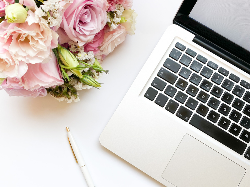 Computer pictured next to a bouquet of flowers