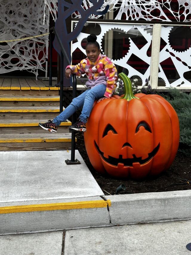 Annalise sitting on a cute Halloween pumpkin at Hersheypark's Dark Nights.